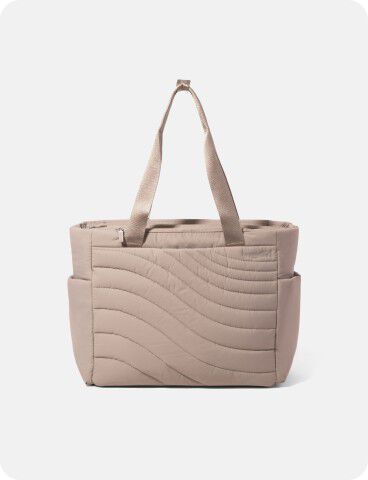 Beige quilted tote bag with wave pattern, two long handles, and side pockets, displayed against a plain light background.