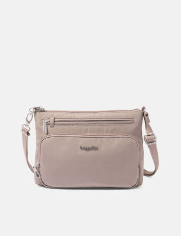 A taupe crossbody bag with adjustable strap, two front zippered pockets, and silver hardware, displayed against a plain white background.