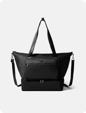 A black tote bag with dual handles, a detachable shoulder strap, a front zip pocket, and a rectangular bottom compartment, displayed against a plain light background.